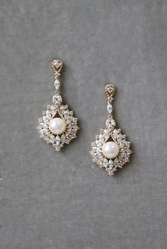 two pairs of pearl and crystal earrings on a gray surface, one with a white bead