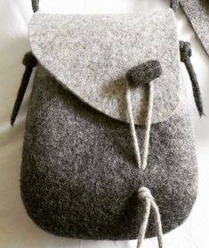 a gray and white purse sitting on top of a bed next to another bag with two handles