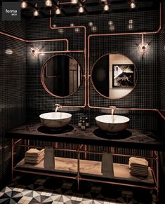 a bathroom with two sinks, mirrors and lights on the wall above them is decorated in black and gold