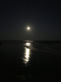 the moon shines brightly in the dark night sky over the water at the beach