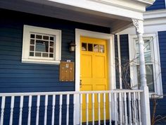 a blue house with yellow door and white railing