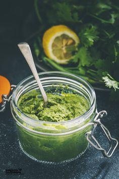 a jar filled with green pest and garnished with cilantro on the side