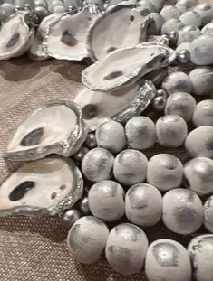 an assortment of oysters are displayed on a cloth covered table with silver foiled beads