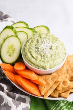 a plate with crackers, cucumber and carrots on it