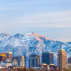 a city with mountains in the background and snow on the top of the mountain tops