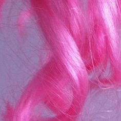 pink hair is shown from above on a white surface with light reflection in the background