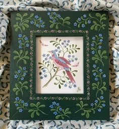 a green frame with blue flowers and a bird on it