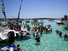 many people are swimming in the water near boats