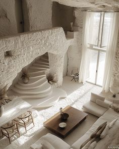 a living room filled with white furniture and a stone fire place next to a window