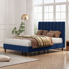 a bed with blue upholstered headboard and foot board in a white room