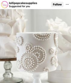 a white wedding cake with beaded decorations on it and the words follow above it