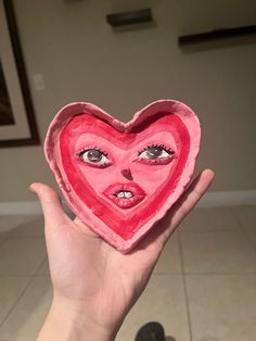 someone holding up a heart shaped paper cutout with their face painted on the inside