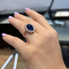 a woman's hand holding a ring with a blue and white stone in it