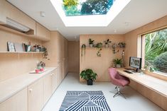 a home office with skylights and plants on the desks in front of it