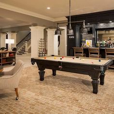 a pool table in the middle of a living room with chairs and tables around it