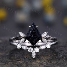 a black diamond ring with three pear shaped diamonds on the side and two pear shaped diamonds on the other side