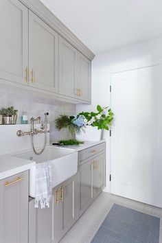 a kitchen with white cabinets and green plants on the counter top, along with a sink