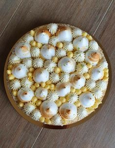 a cake with white and yellow toppings on a wooden table next to a knife