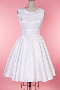 a white dress on a mannequin stand against a pink background, with the back of it's neckline showing