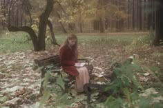 a woman sitting on a bench in the woods