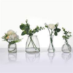 four vases with flowers in them sitting on a table