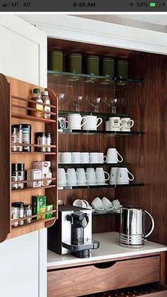 an open cabinet with many cups and coffee mugs on the shelves next to it