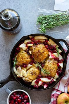 a skillet filled with meat, apples and cranberries