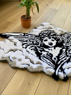 a black and white rug on the floor next to a potted plant