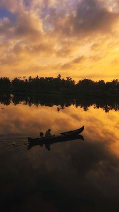 two people in a canoe on the water at sunset