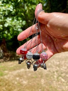 a person is holding several small bells in their hand and there are trees in the background