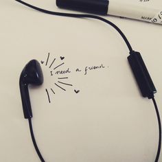 a pair of black ear buds sitting on top of a white table next to a pen