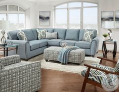 a living room with blue couches and pillows on the floor in front of large windows