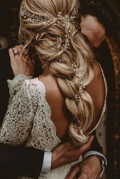 the back of a bride's head is shown with her hair in a braid