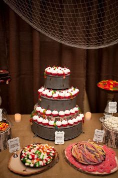 a table topped with cakes and desserts covered in frosting on top of wooden slices