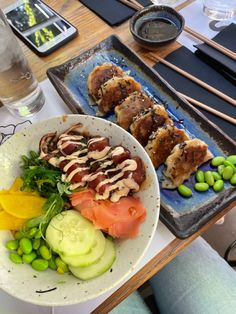 a bowl of food on a table with chopsticks and water in the background