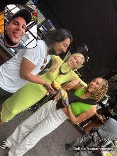 two women and a man are posing for a photo while one woman is holding a cell phone