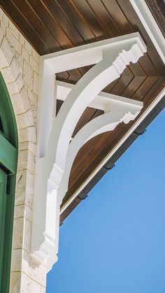 a green door and white arch on a brick building with blue sky in the background