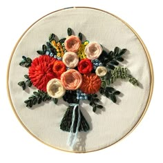 a bouquet of flowers on a white wall hanging in a hoop with thread and beads