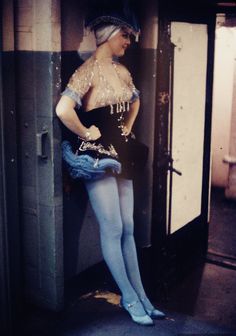 a woman dressed in costume standing next to an open door with her hands on her hips