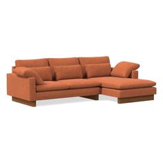 an orange sectional couch with pillows on the top and bottom, in front of a white background