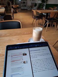 an open laptop computer sitting on top of a wooden table next to a cup of coffee