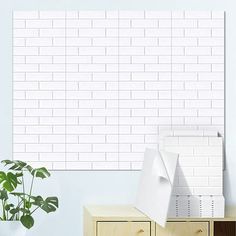 a white brick wall next to a plant in a room with blue walls and drawers