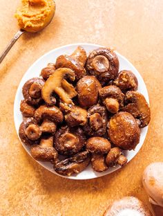 a white plate topped with mushrooms next to a spoon