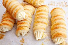 four croissants with cream on them are sitting on a piece of parchment paper