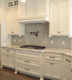 a kitchen with white cabinets and marble counter tops