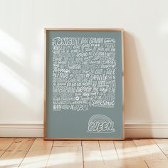 a framed chalkboard with words written in different languages on the wall next to a wooden floor