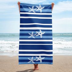 a person holding up a blue and white towel with two starfishs on it