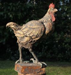 a statue of a rooster standing on top of a wooden block