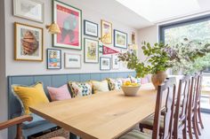 a dining room table with chairs and pictures on the wall above it, along with potted plants