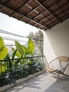 a wooden chair sitting on top of a balcony next to a green plant covered roof